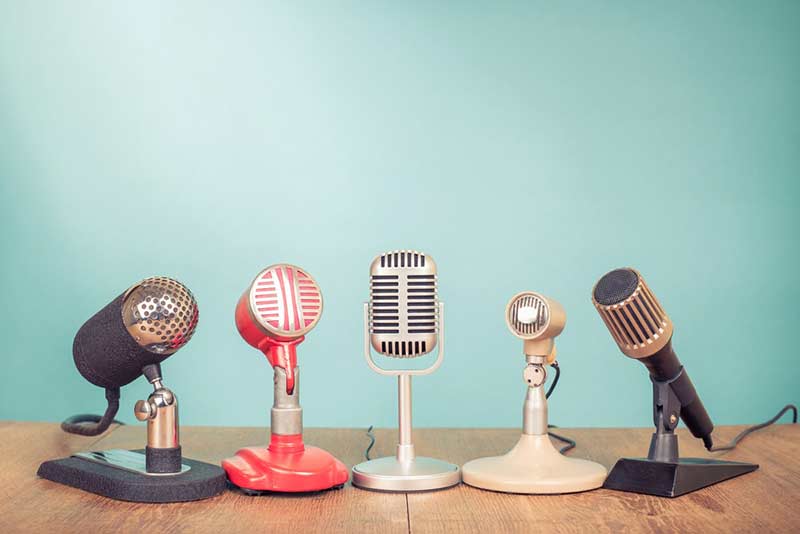 row of 5 old fashioned microphones