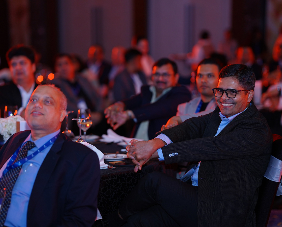 Attendees seated at round tables during the Orbus Dubai Launch Celebration, attentively watching a presentation. Several individuals are smiling.